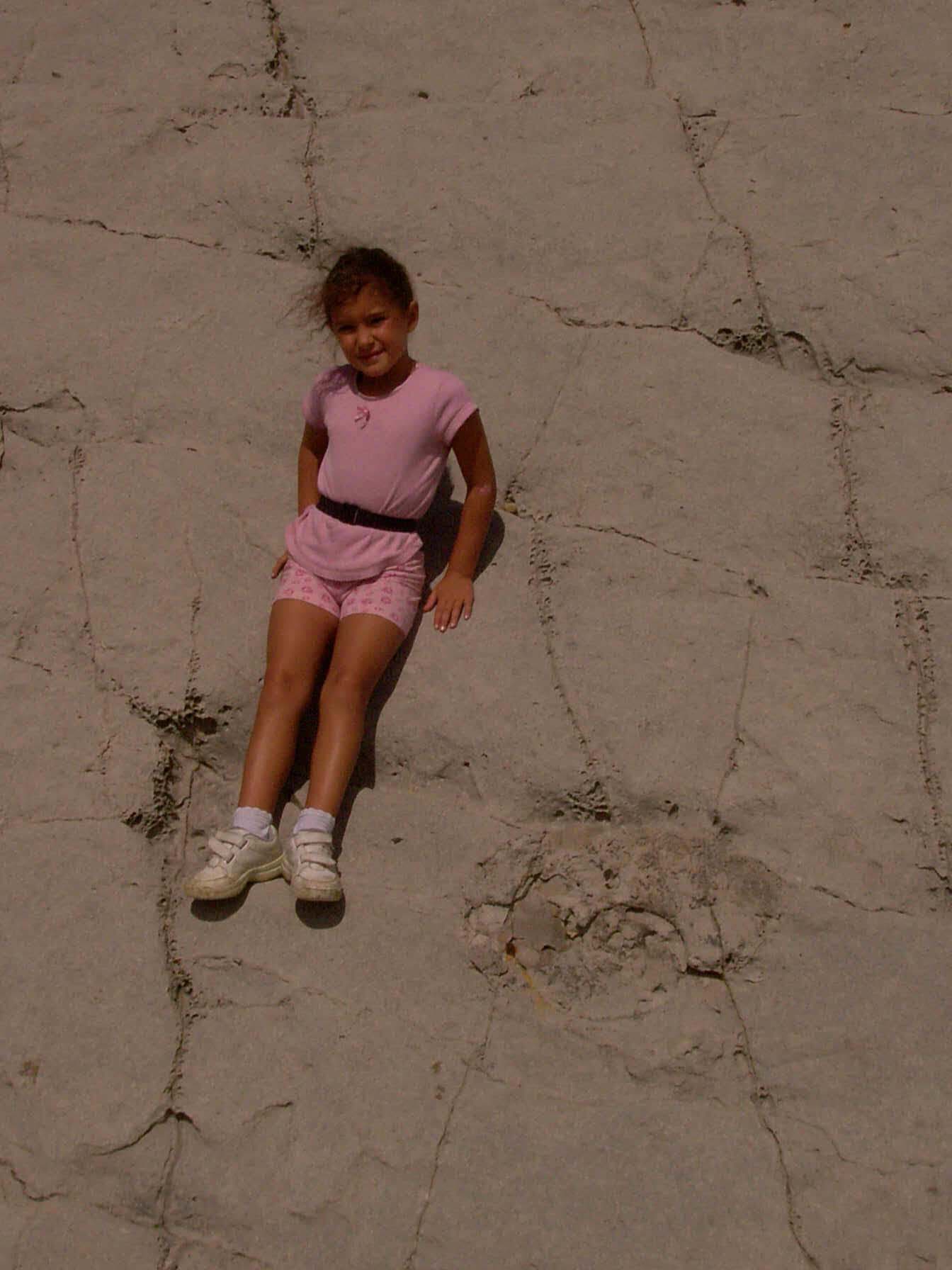 Imagen de una niña al lado de un fósil, en una pendiente de roca caliza. Imagen: De Mier y Leva.